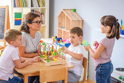 Frau und Kinder spielen in Kita