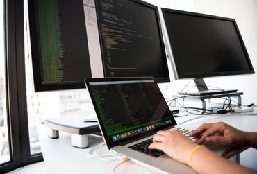 Programmierer arbeitet an mehreren Bildschirmen