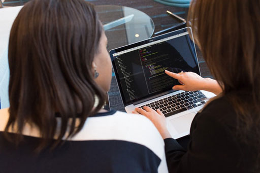 Zwei Personen arbeiten gemeinsam an Quellcode